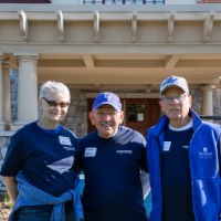 3 class of 1967 Alumni stand in front of Alumni House and Visitor's Center